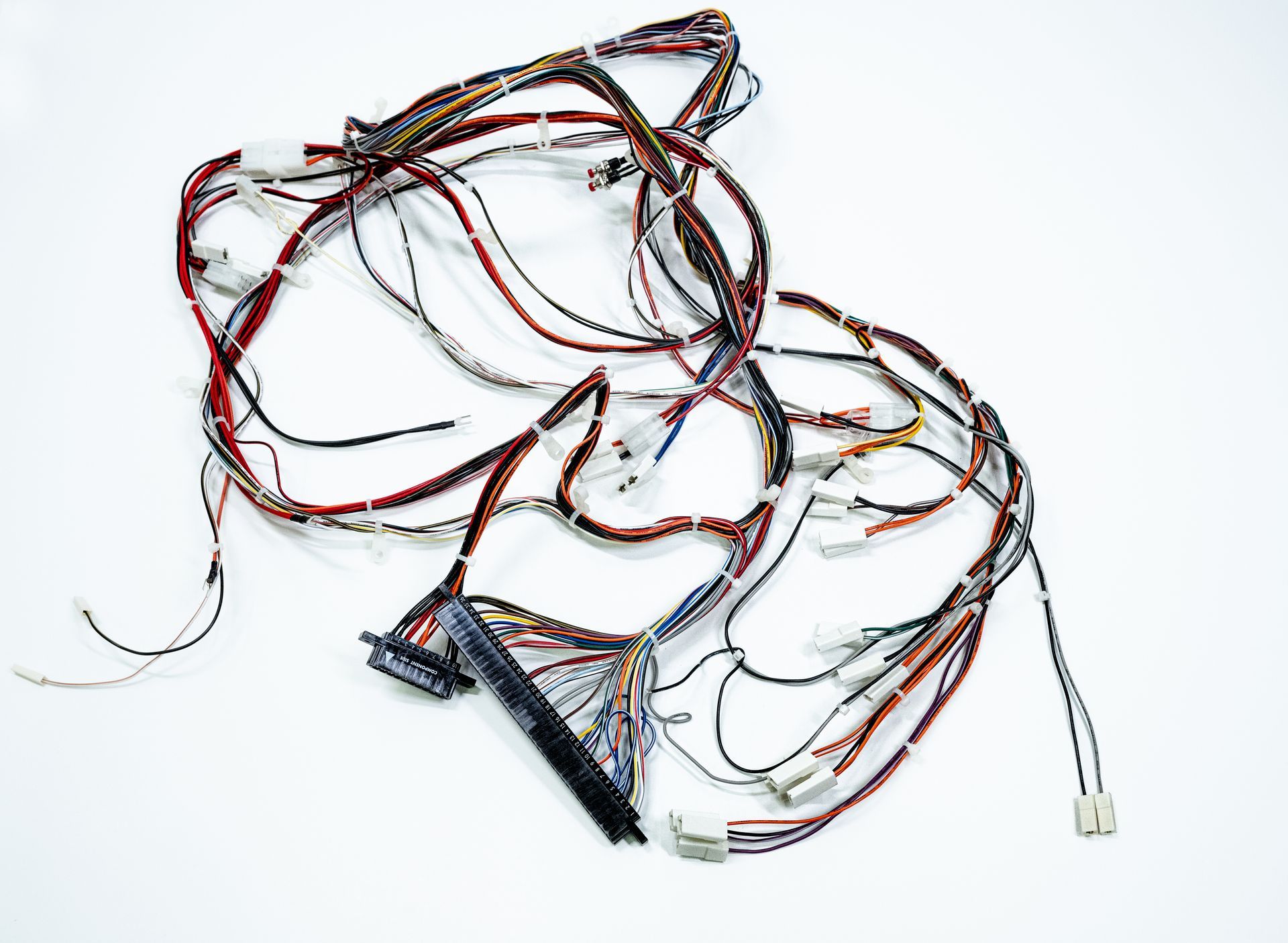 Tangled bundle of colorful electrical wires with connectors, lying on a white surface.