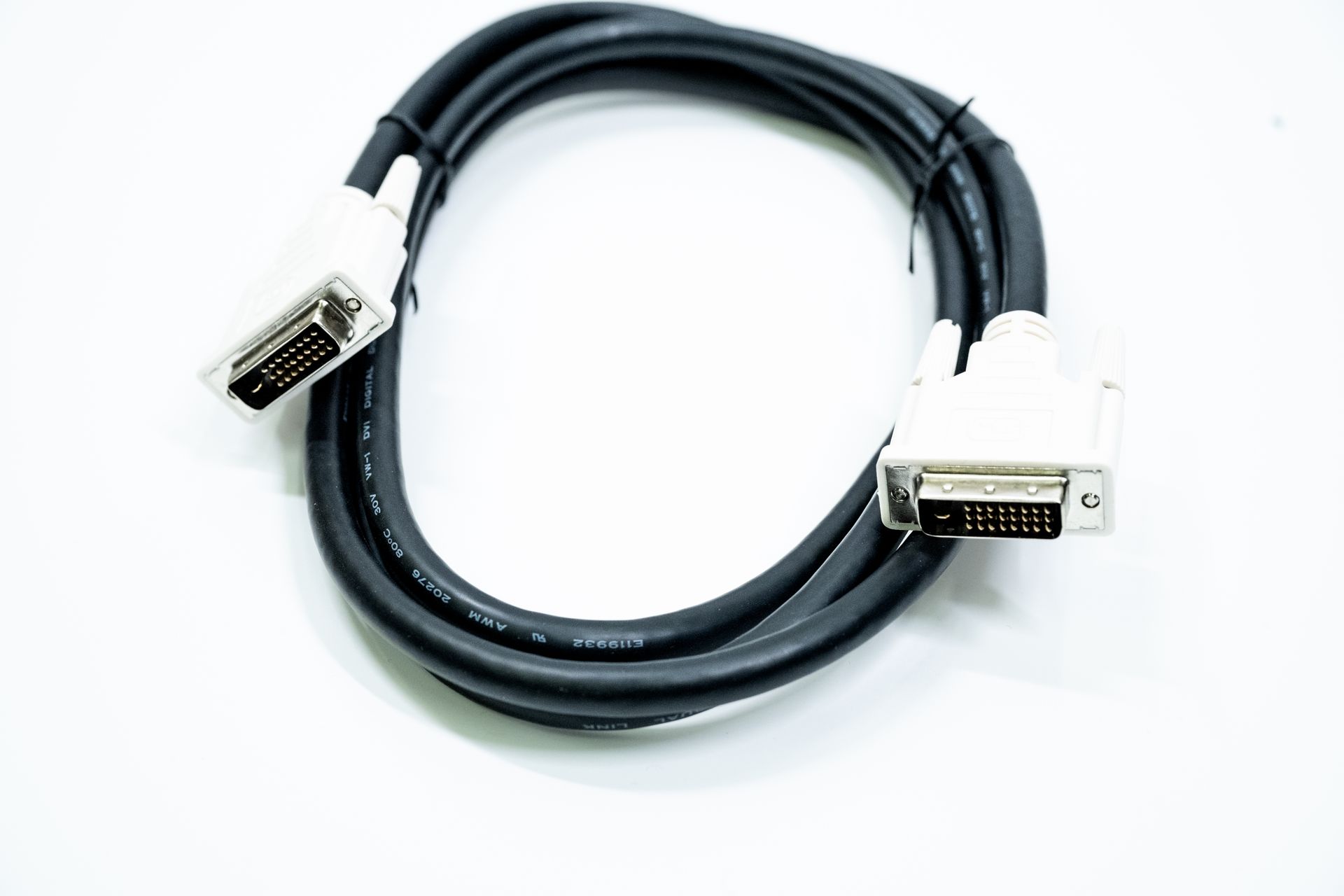 A black DVI cable with white connectors coiled against a white background.