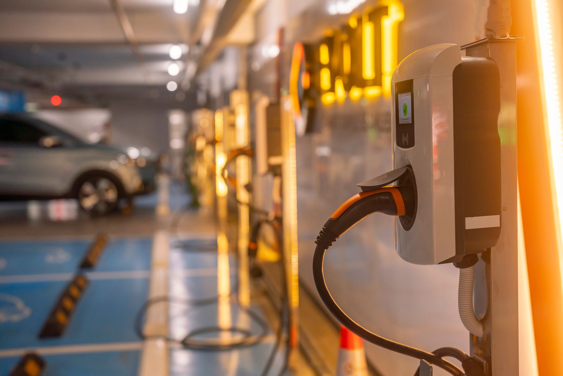An electric car is being charged at a charging station in a parking garage.