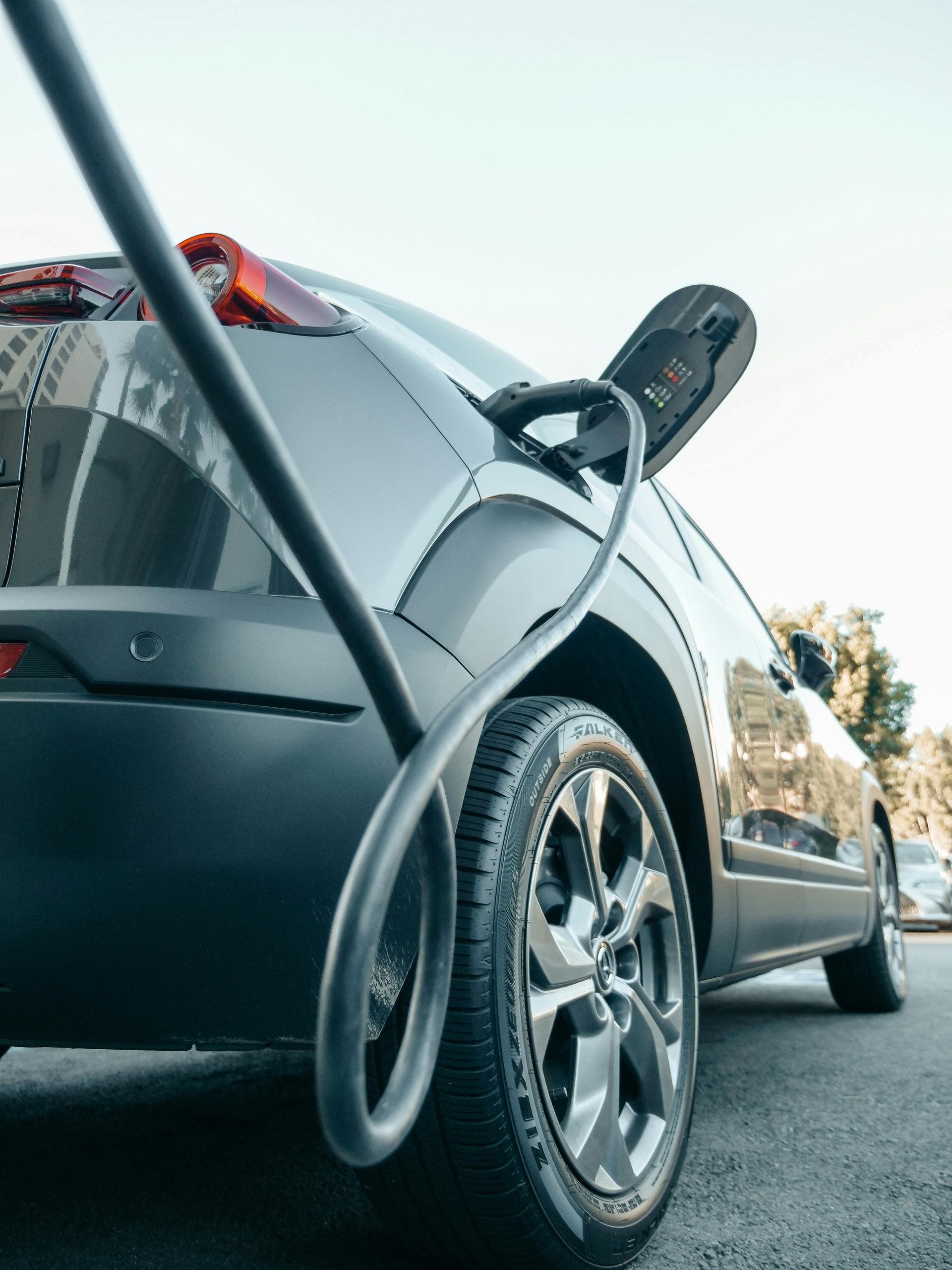 An electric car is being charged at a charging station in front of a house. An electric car is being charged at a charging station in front of a house.