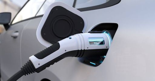 A car is being charged at a charging station in front of a house. A car is being charged at a charging station in front of a house.