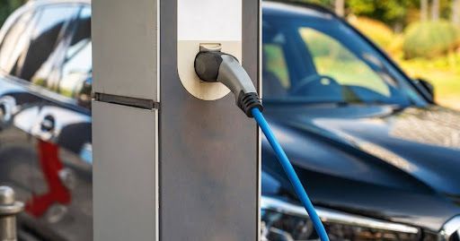 An electric car is being charged at a charging station in front of a house. An electric car is being charged at a charging station in front of a house.