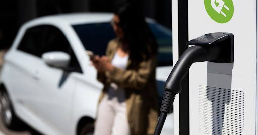 An electric car is being charged at a charging station in front of a house.