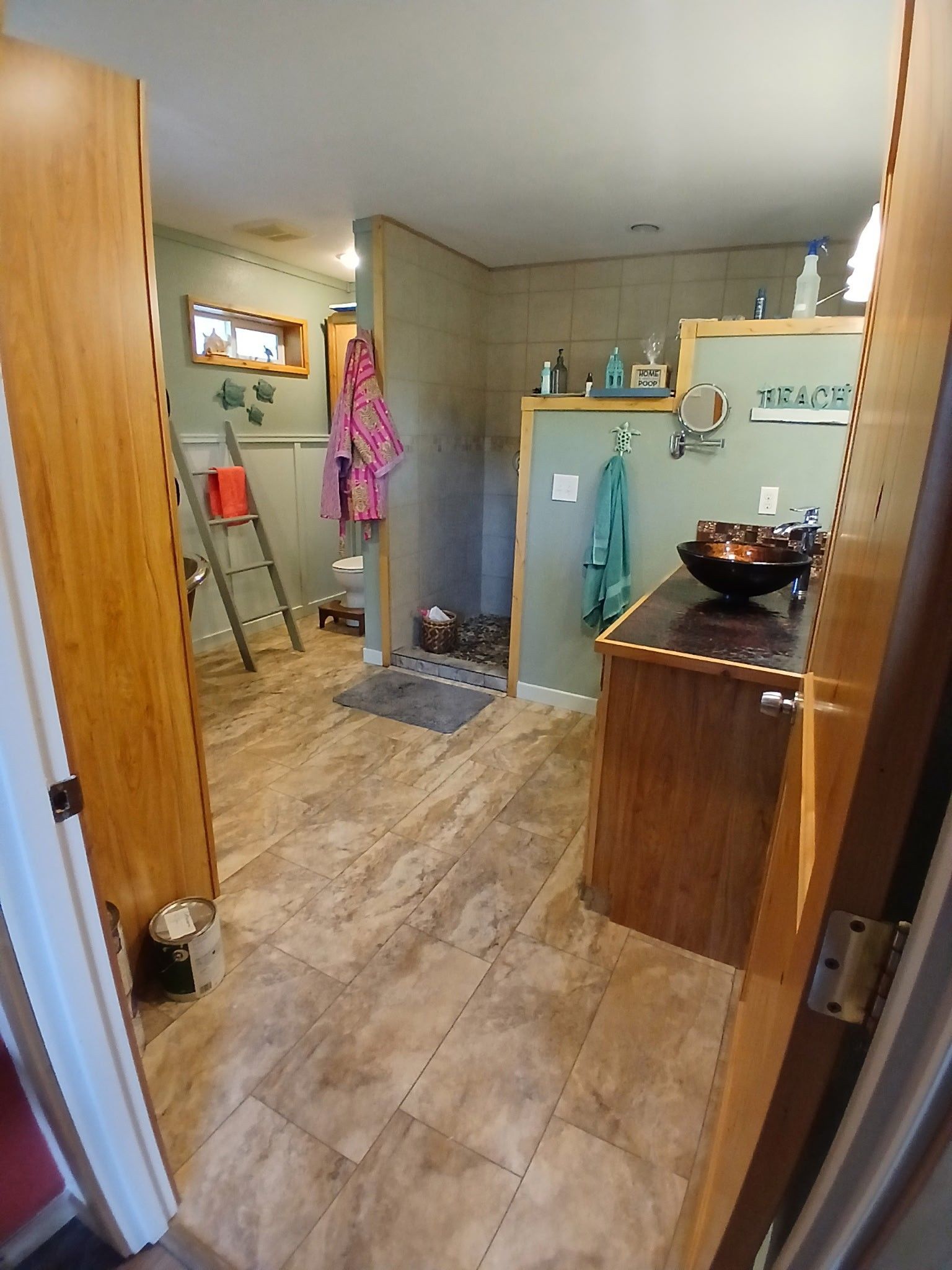 Bathroom with wood trim, brown floors, a shower, and a sink.