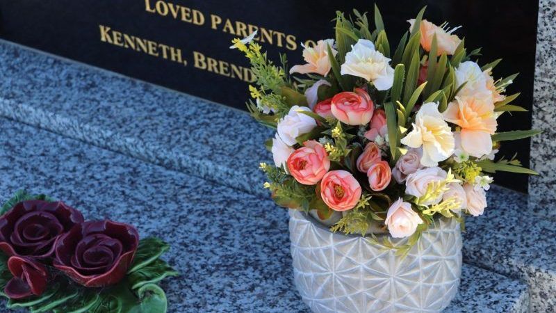 Floral arrangements placed at a memorial site, symbolizing remembrance and honoring loved ones.