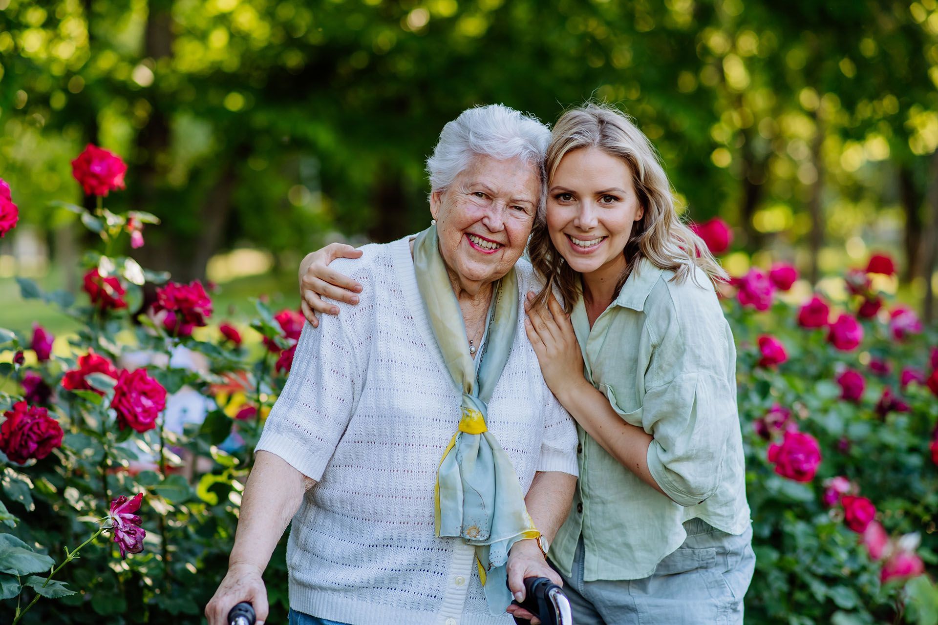 A young woman is hugging an older woman in a park.