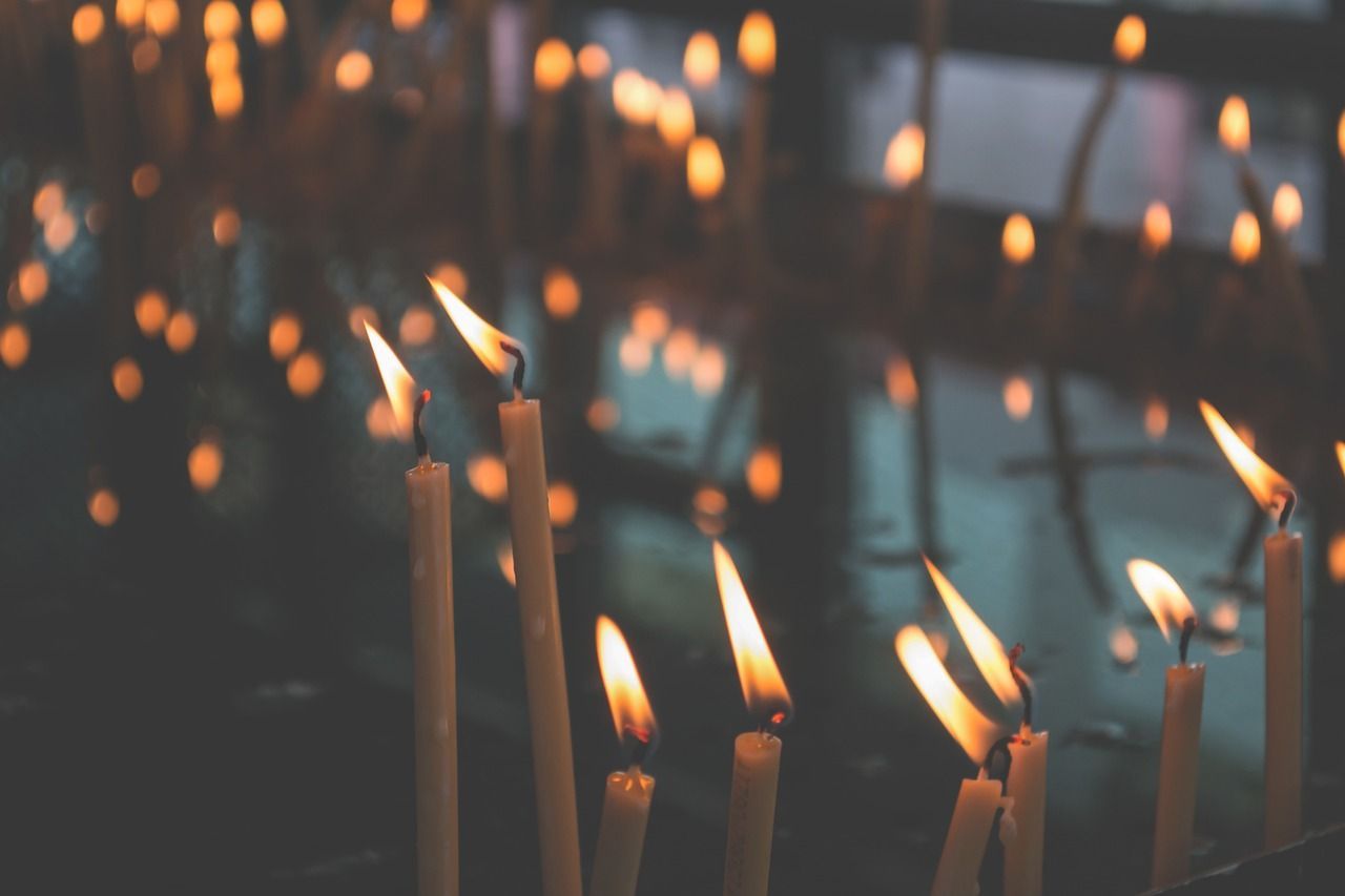 Photo of several lit candles in a dark room