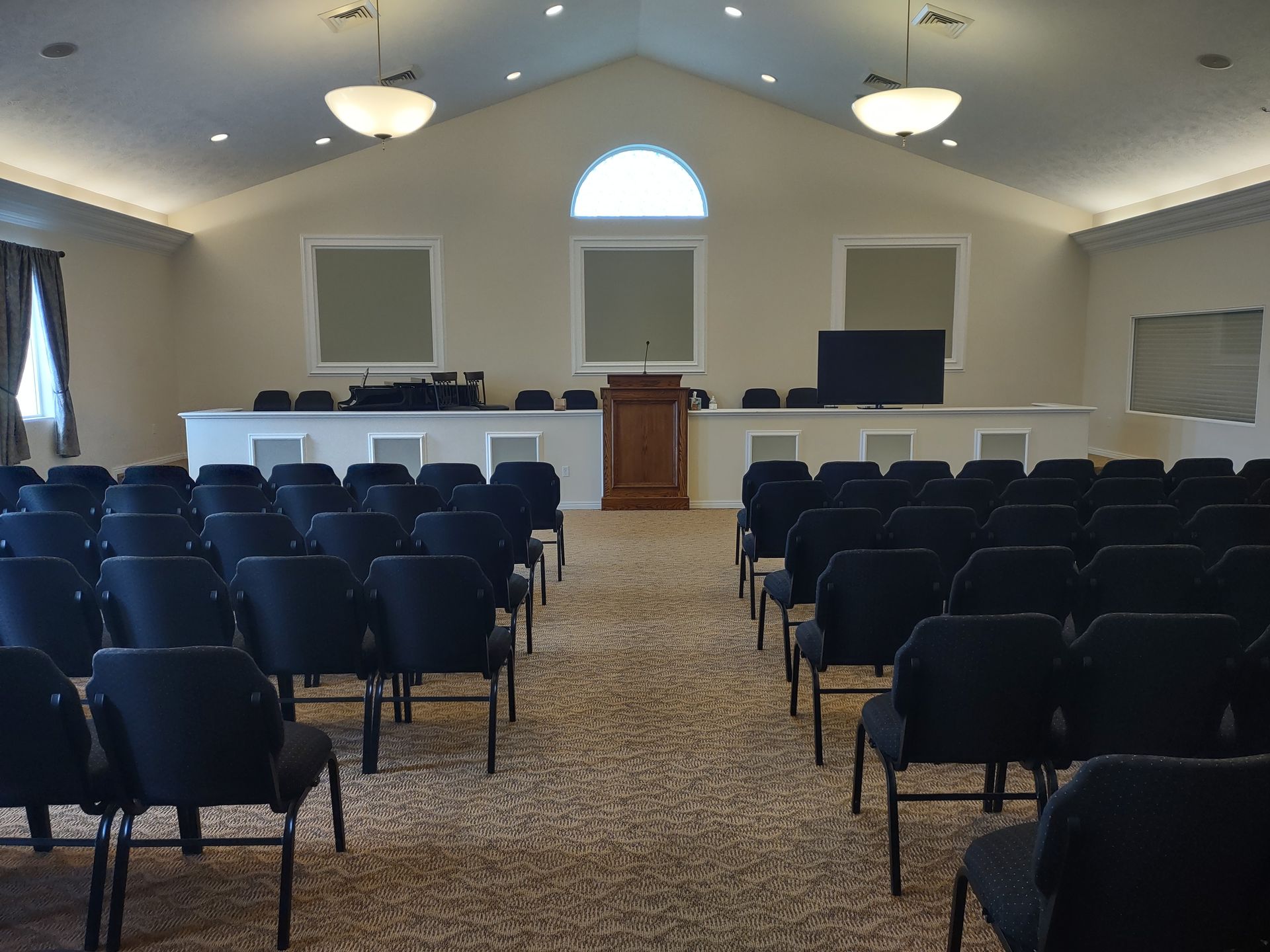 An auditorium with rows of black chairs and a podium