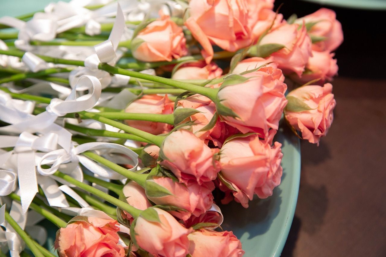 Close-up of pink roses with white ribbons, arranged in a decorative display.