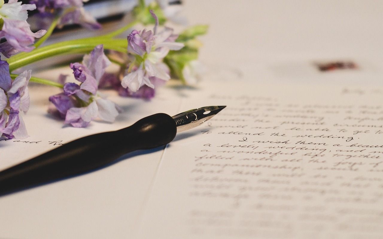 Letter with an ink pen over it, and purple flowers on the corner