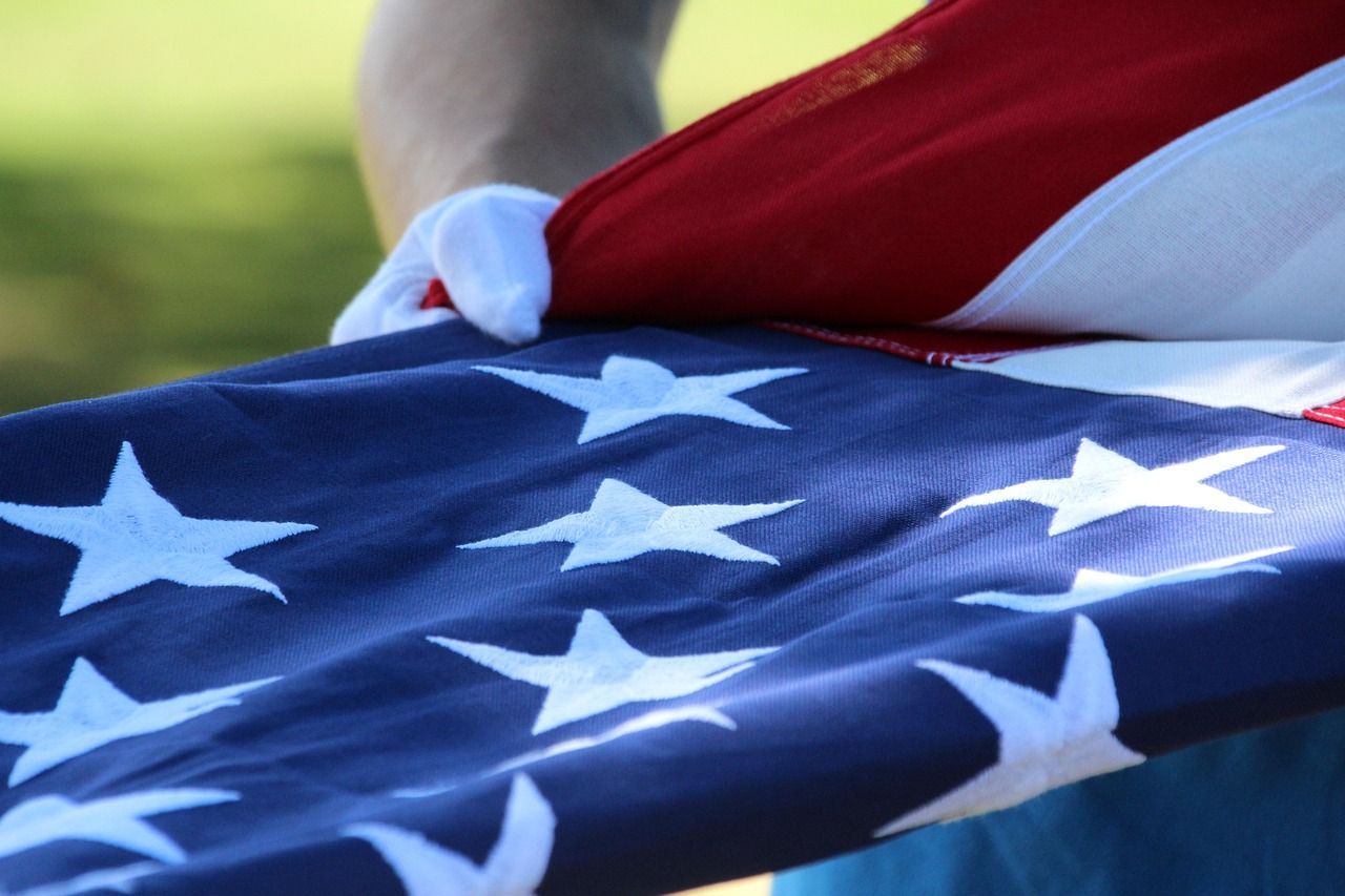 Folded flag of the USA being held by someone wearing a white glove