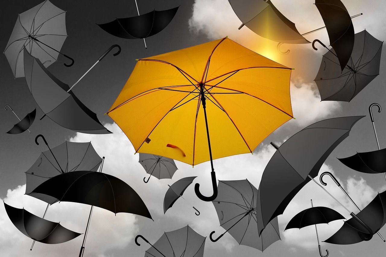Yellow umbrella in between black and white ones