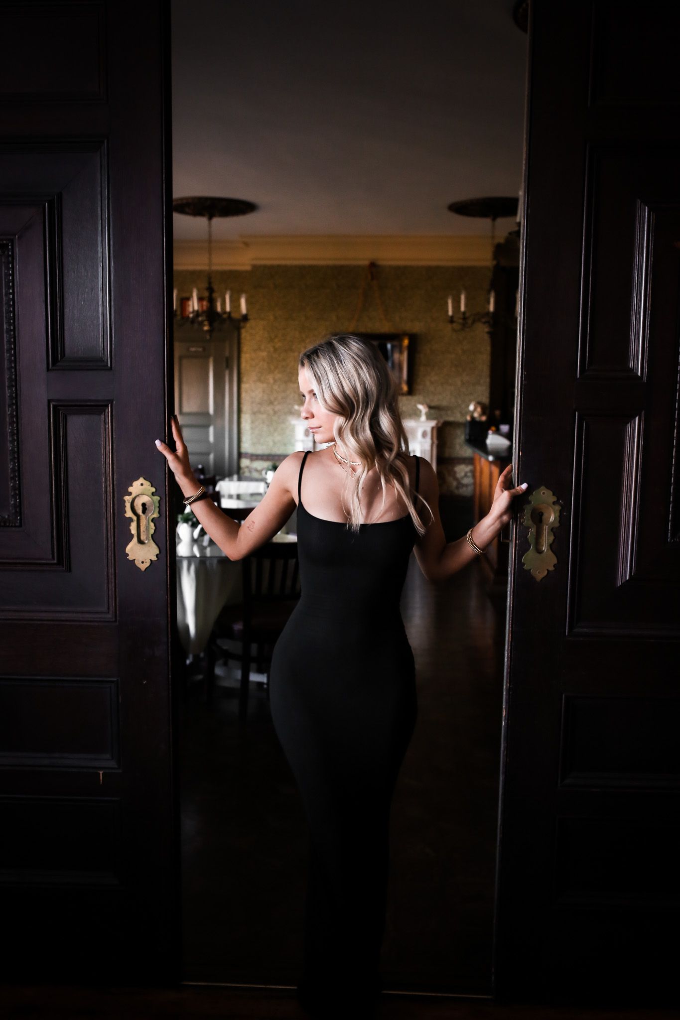 A woman in a black dress is standing in an open doorway.