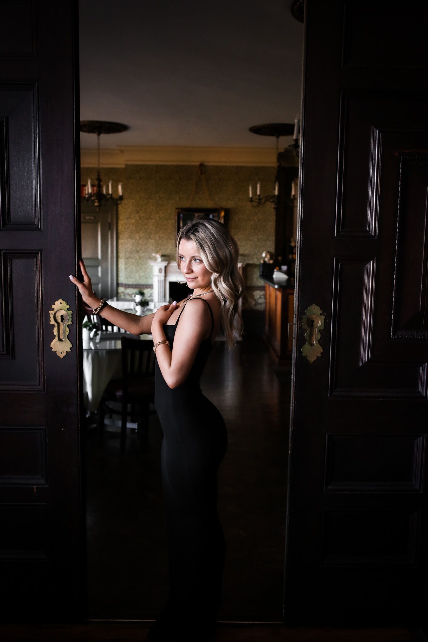 A woman in a black dress is standing in front of a door