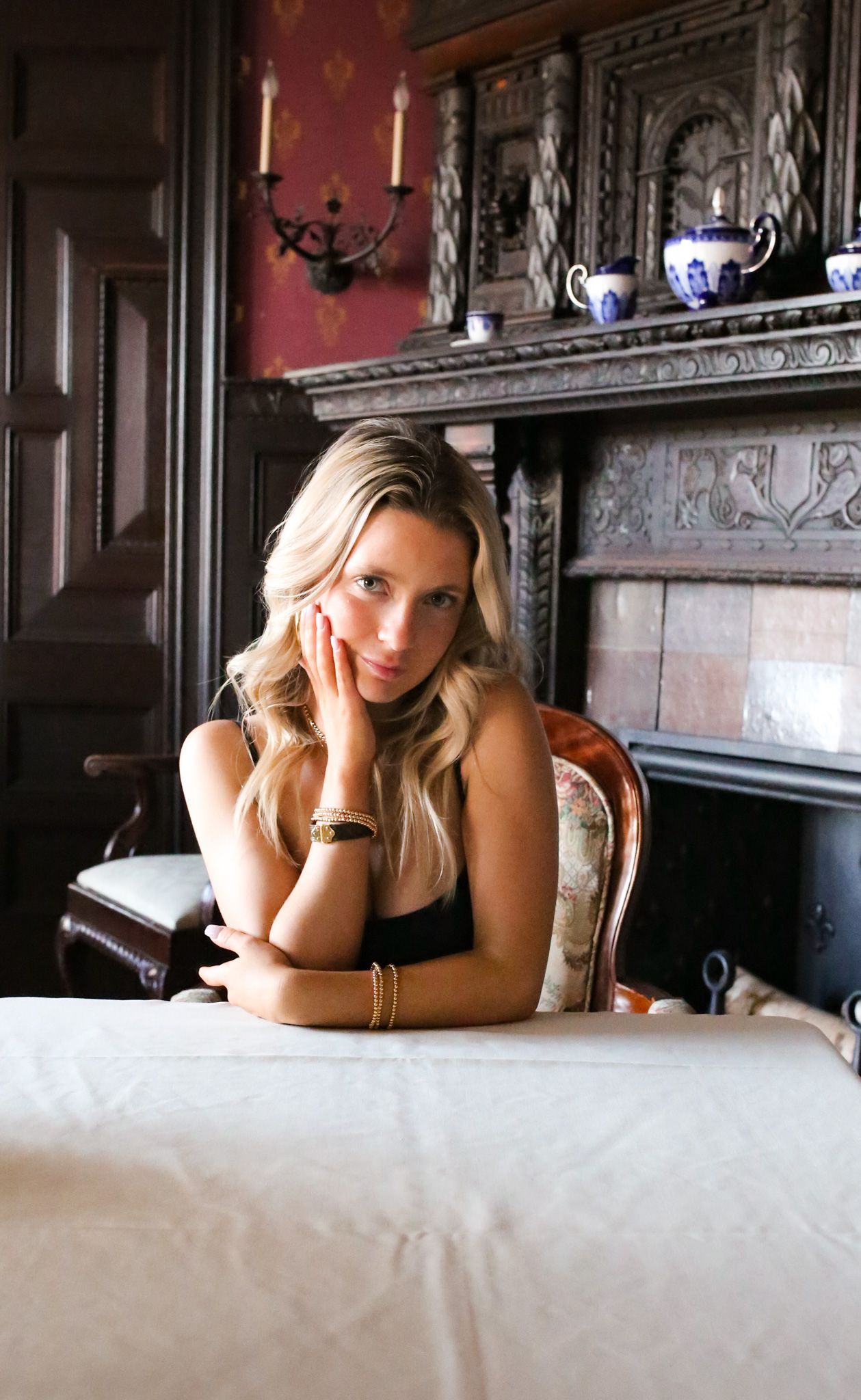 A woman is sitting at a table in front of a fireplace.