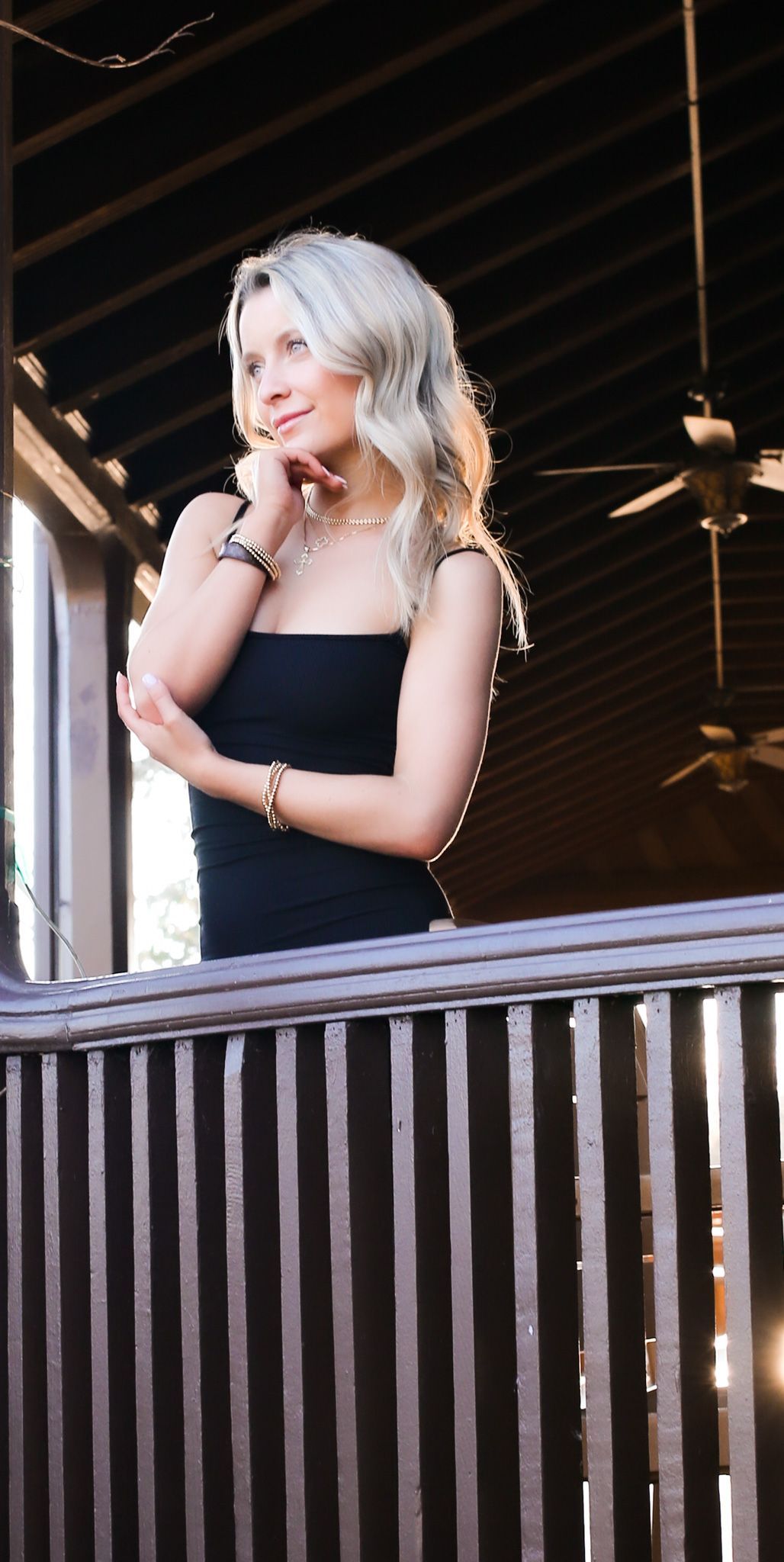 A woman in a black dress is standing on a balcony.
