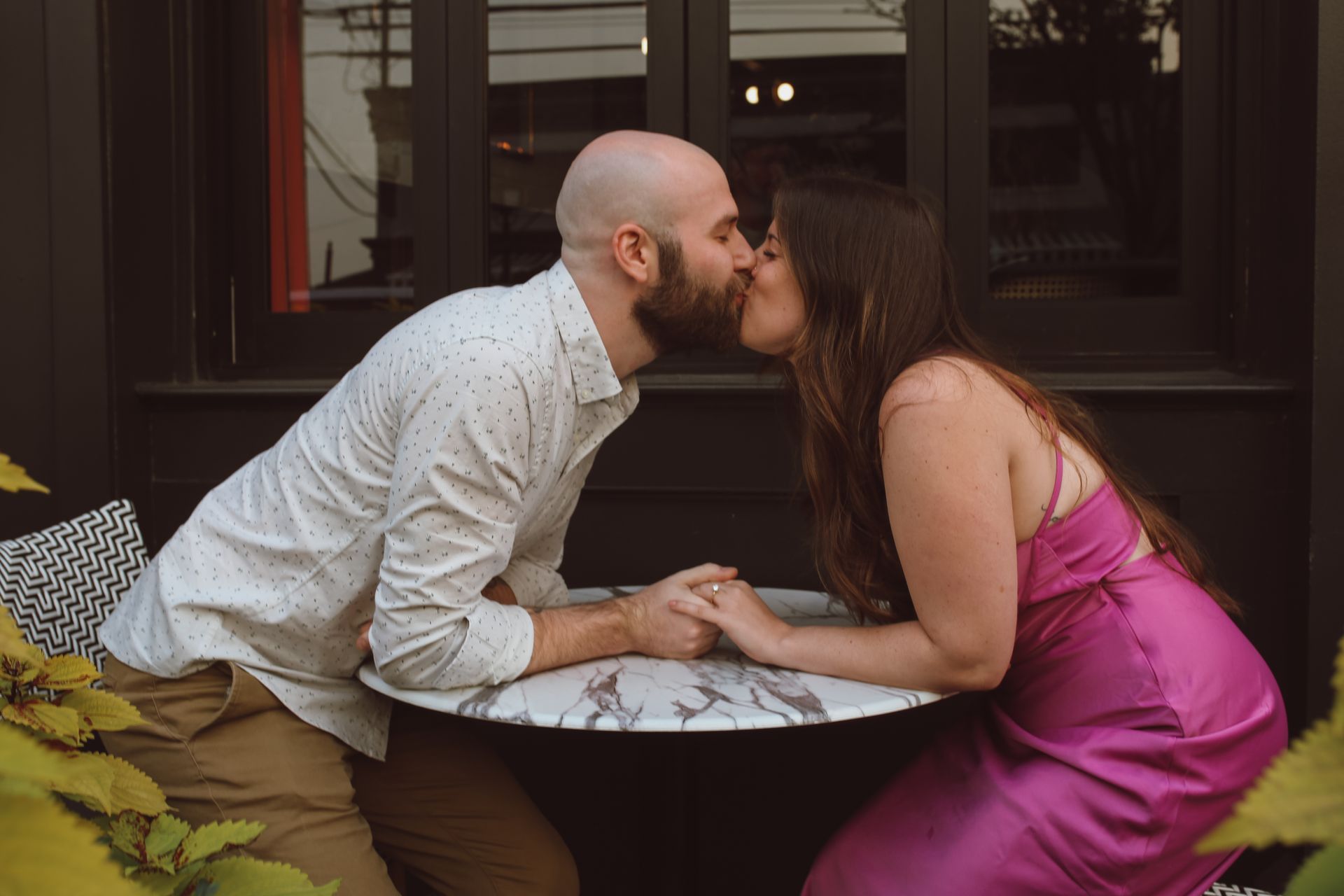 A man and a woman are kissing at a table.