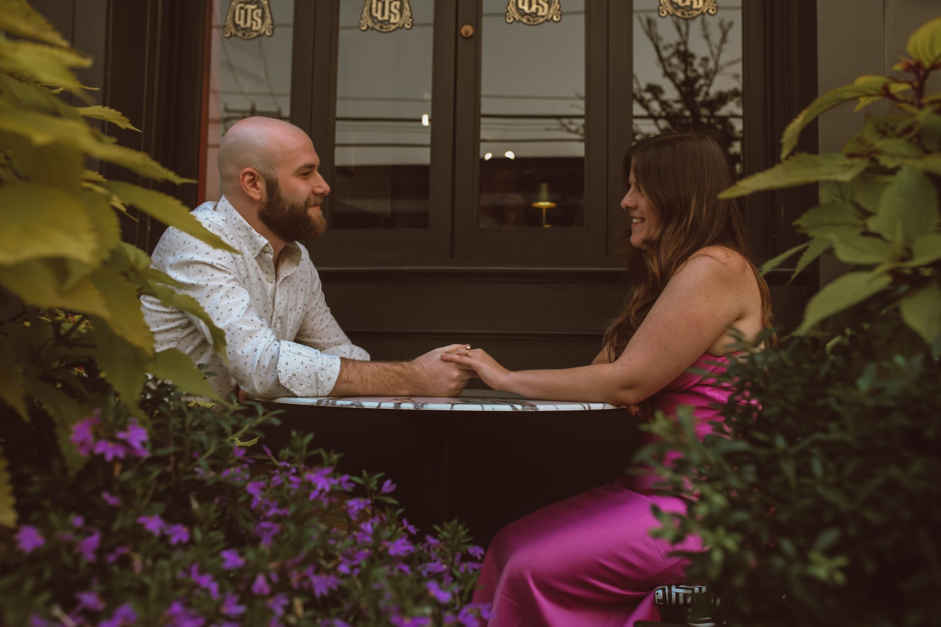 A man and a woman are sitting at a table holding hands.