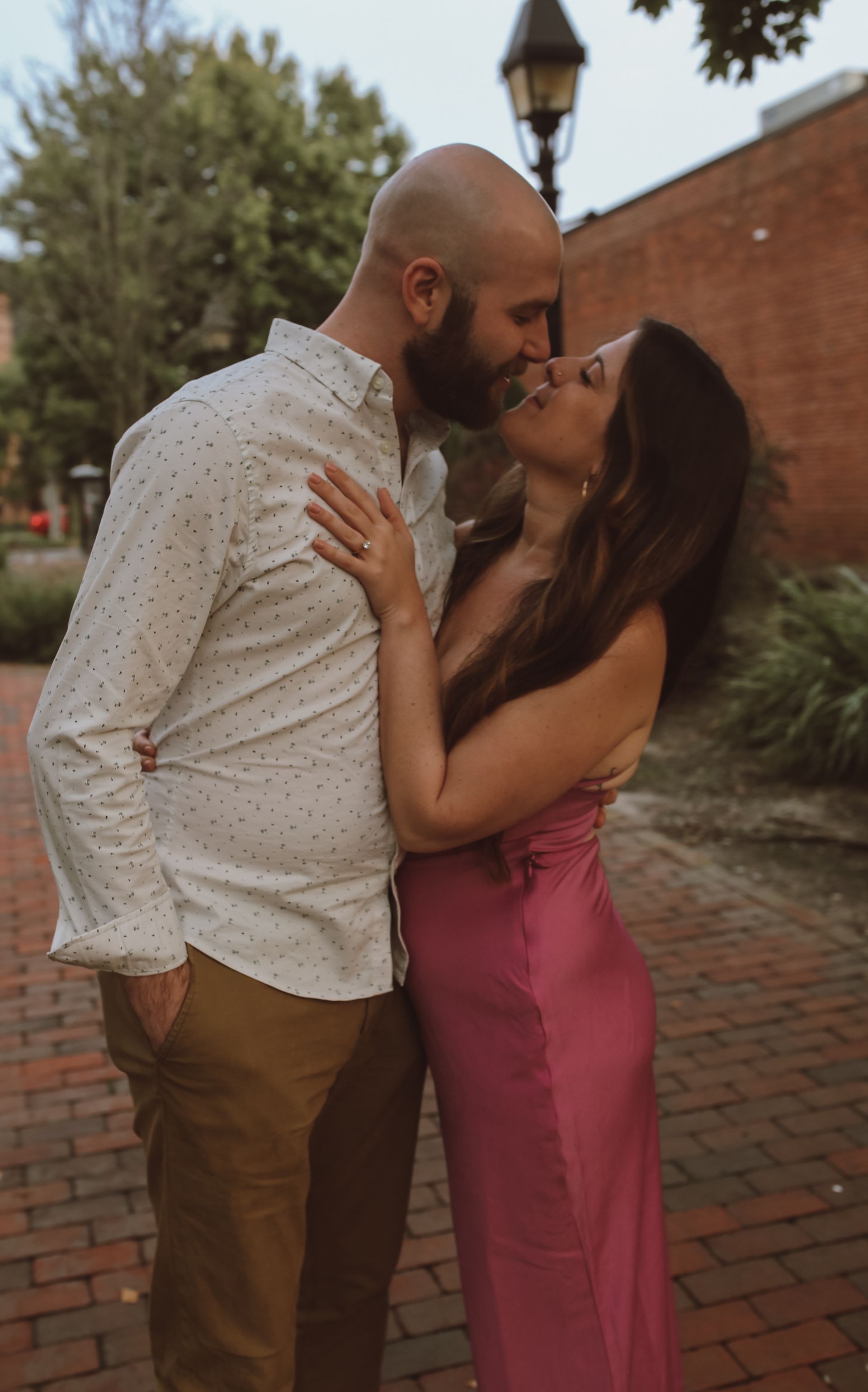 A man and a woman are kissing on a brick sidewalk.