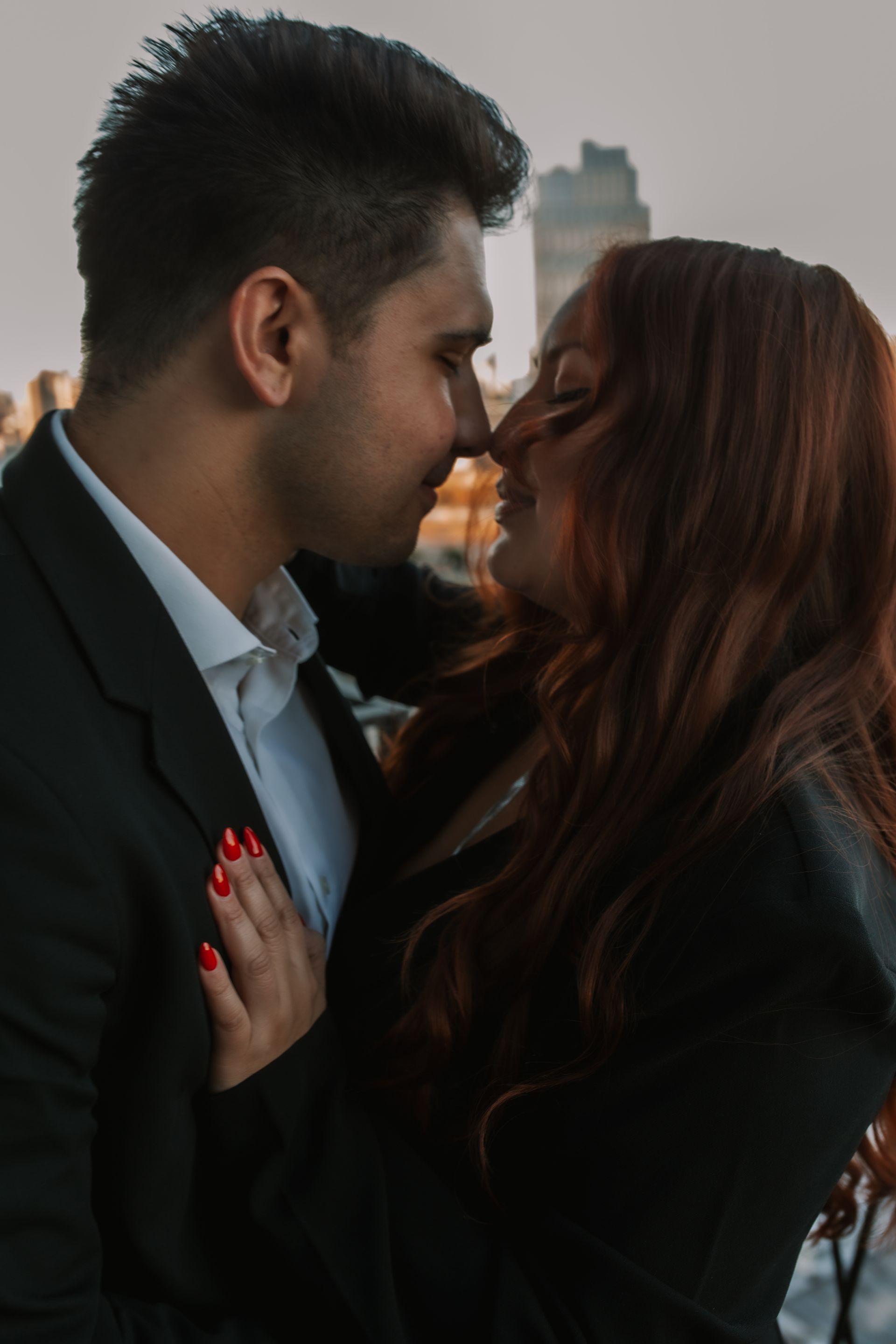 A man and a woman are kissing in front of a city skyline.