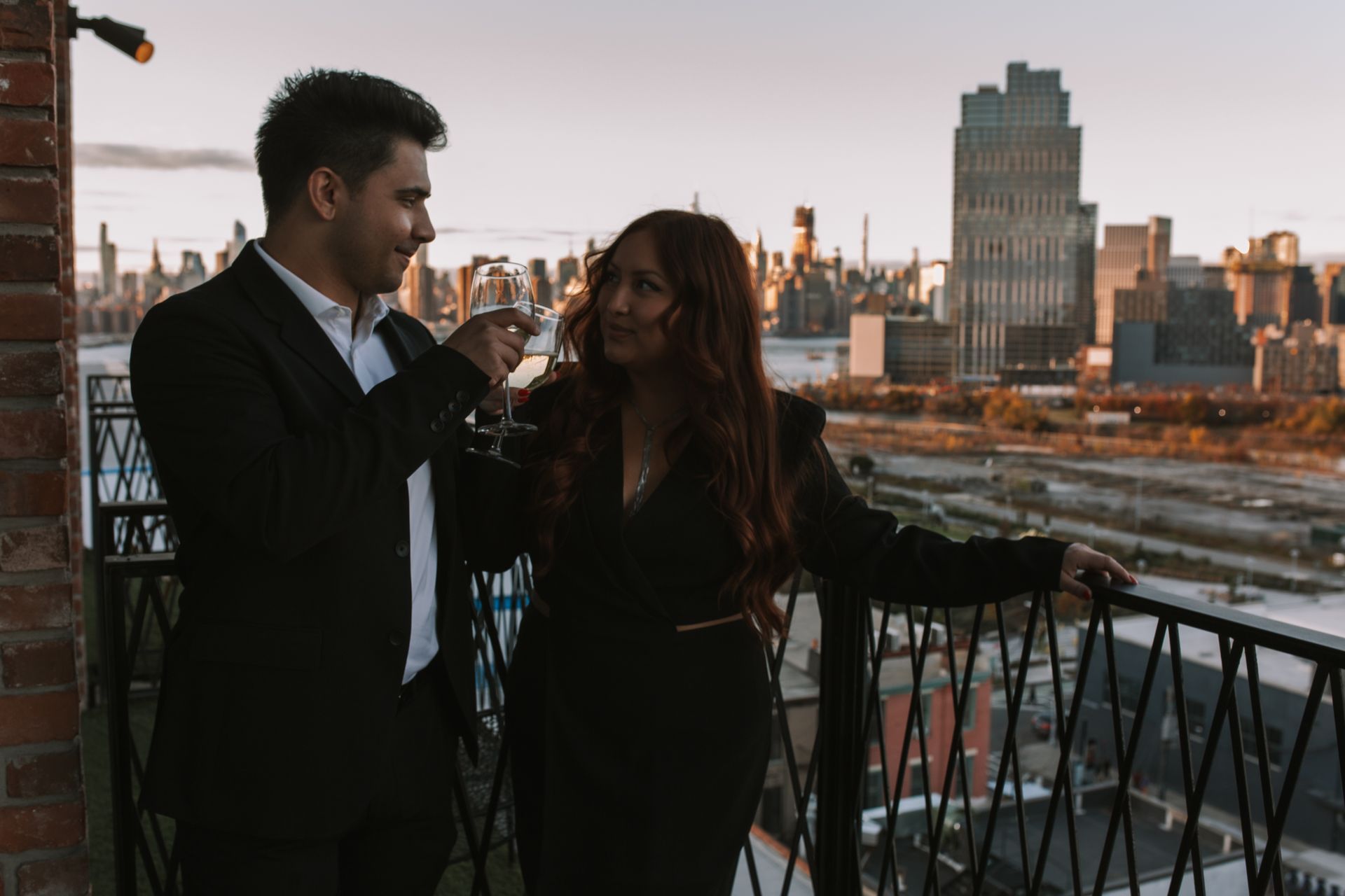A man and a woman are standing on a balcony overlooking a city.