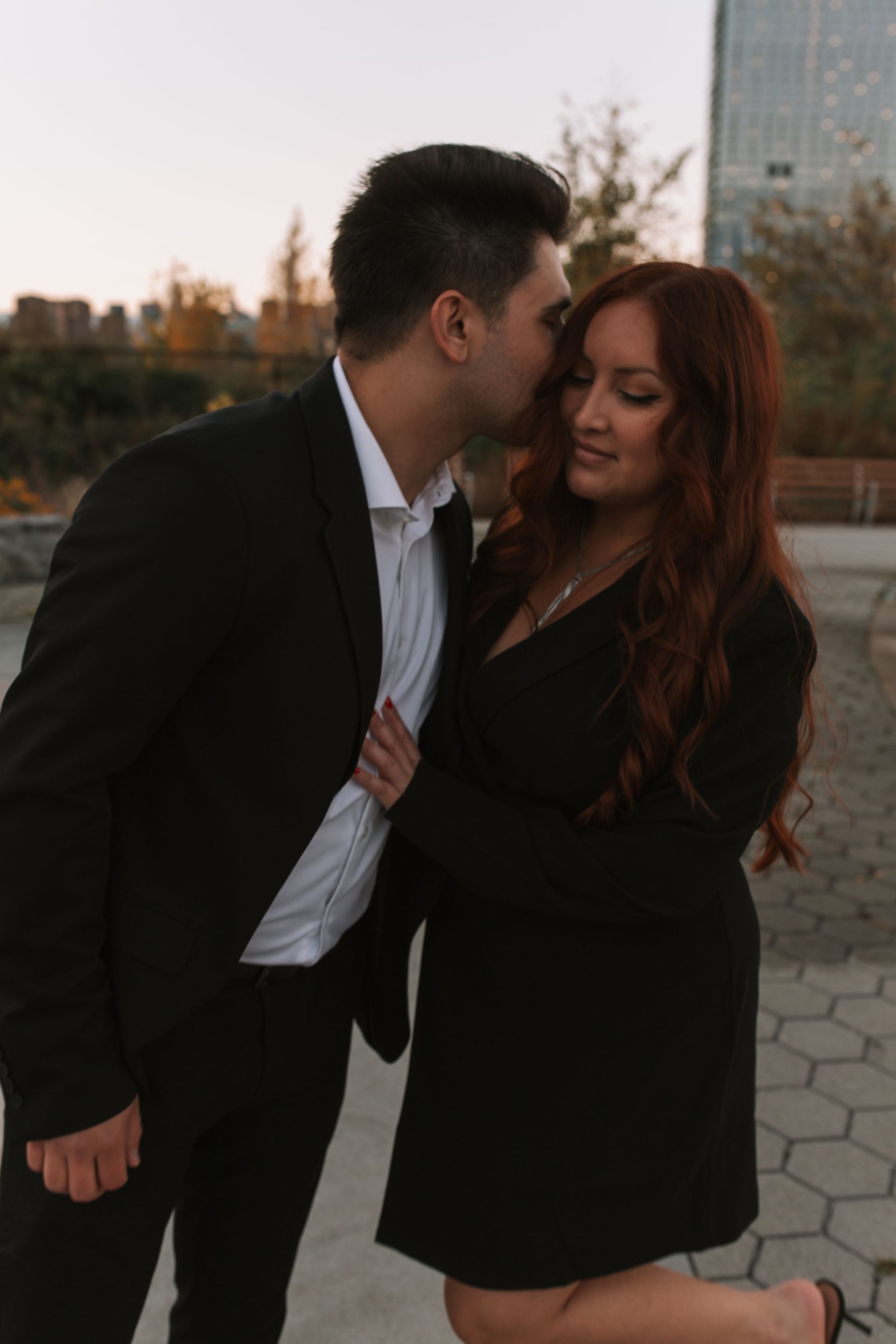 A man in a suit is kissing a woman on the cheek.