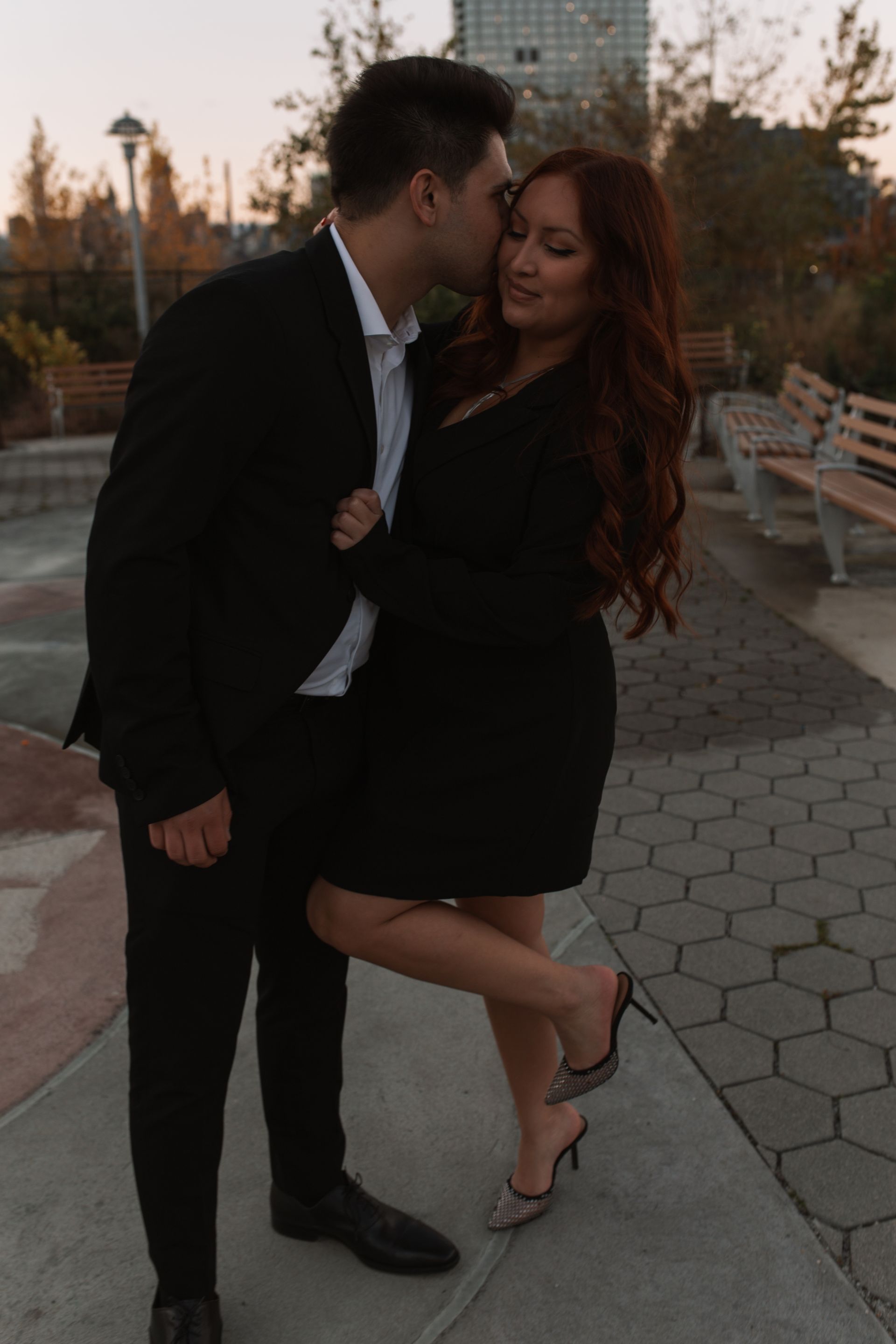 A man in a suit is kissing a woman on the cheek.