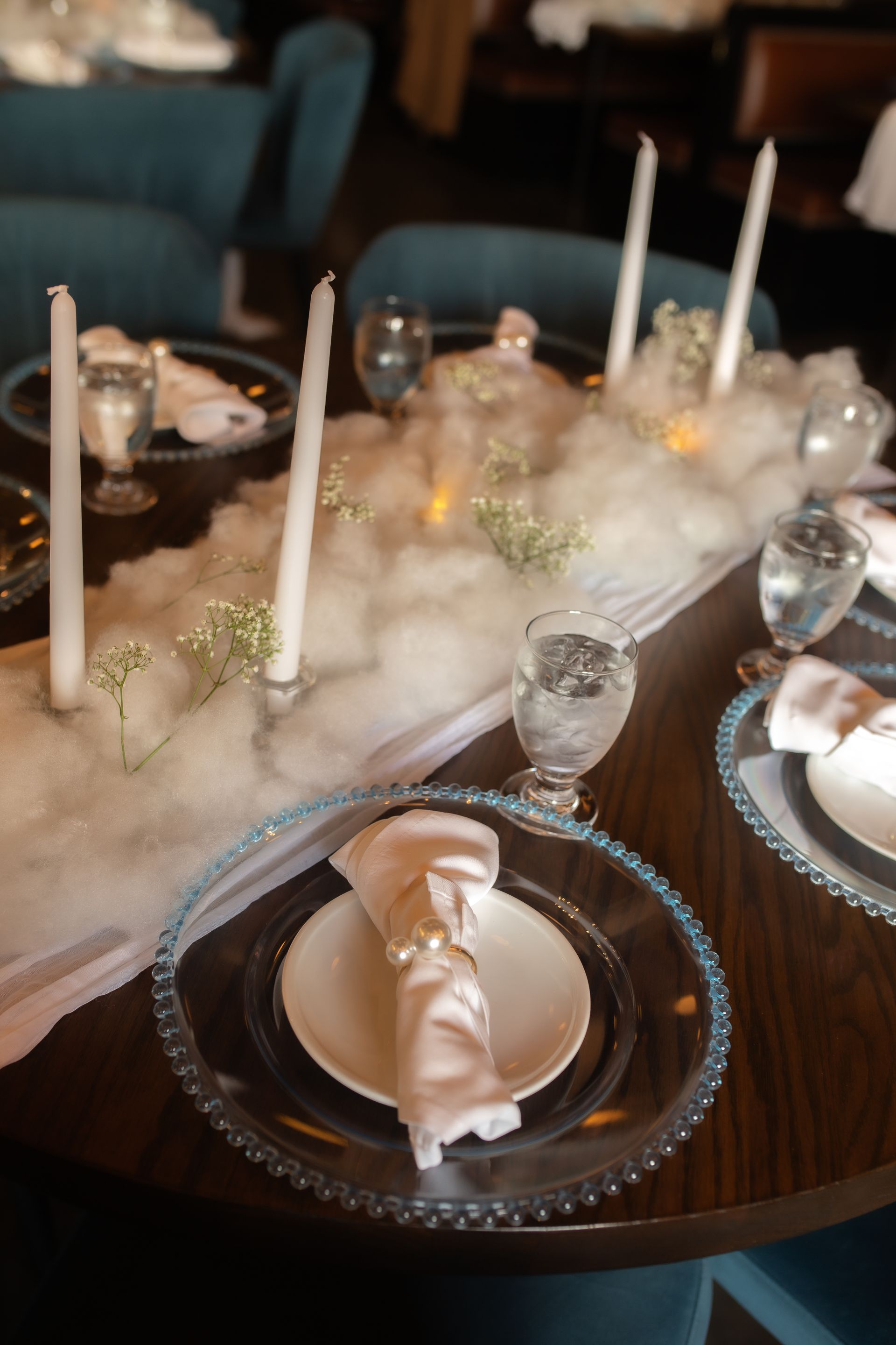 A table set for a wedding reception with plates , candles , and glasses.