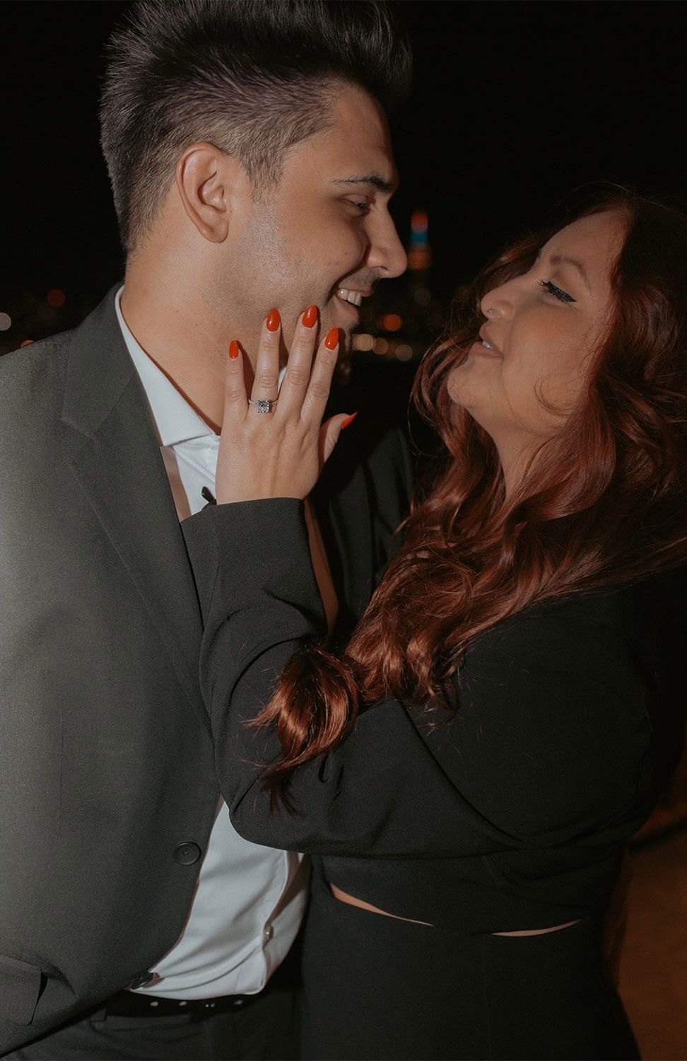 A man and a woman are hugging each other and the woman is wearing a ring on her finger.