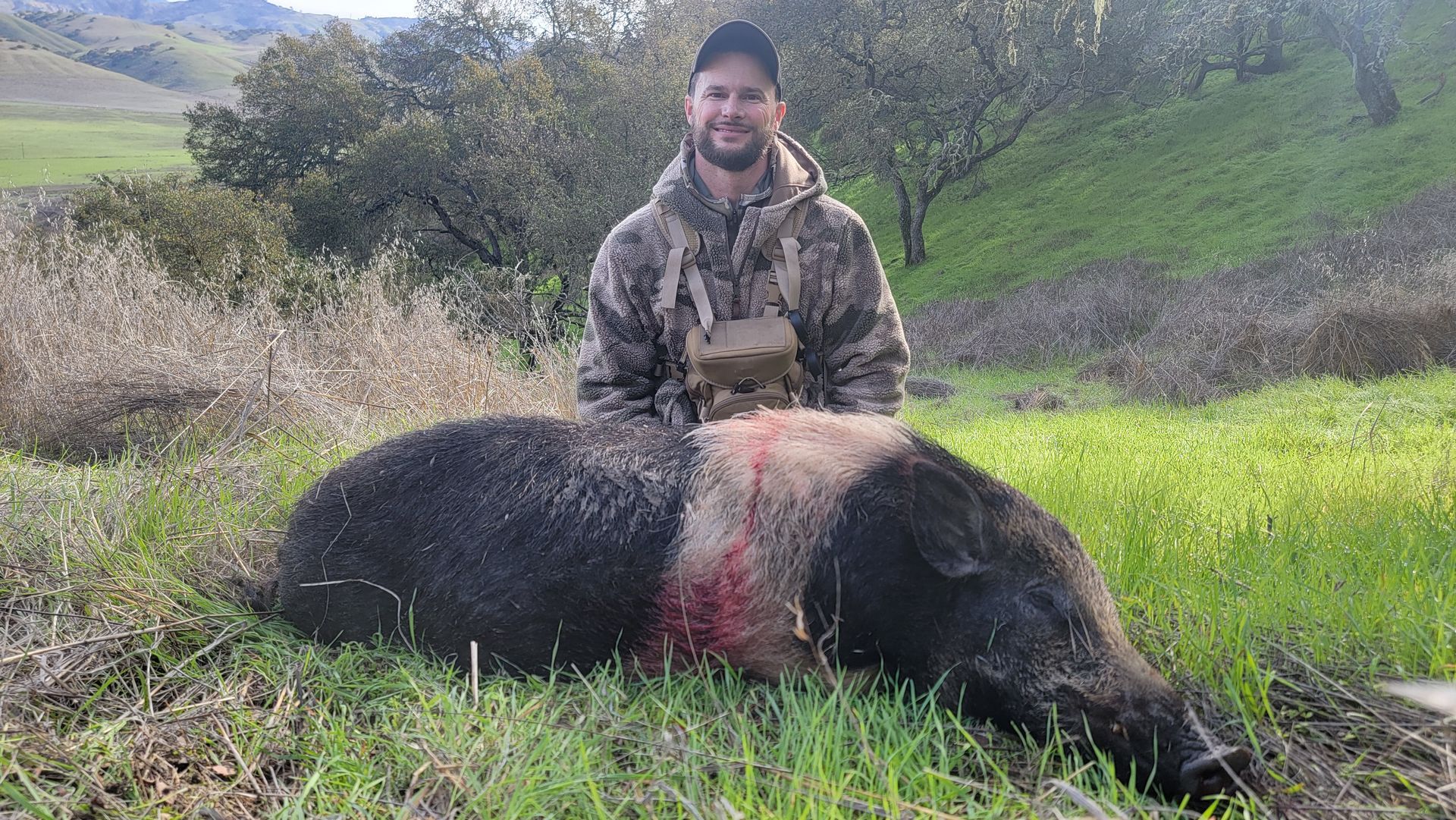 Successful wild hog hunt with hunter posing on Central Coast ranch
