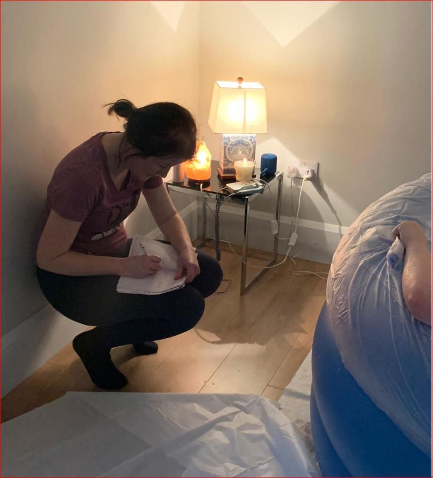 A woman squatting down writing on a piece of paper