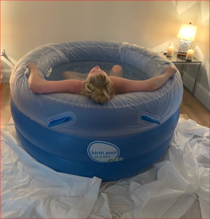 A woman is laying in a blue birth pool