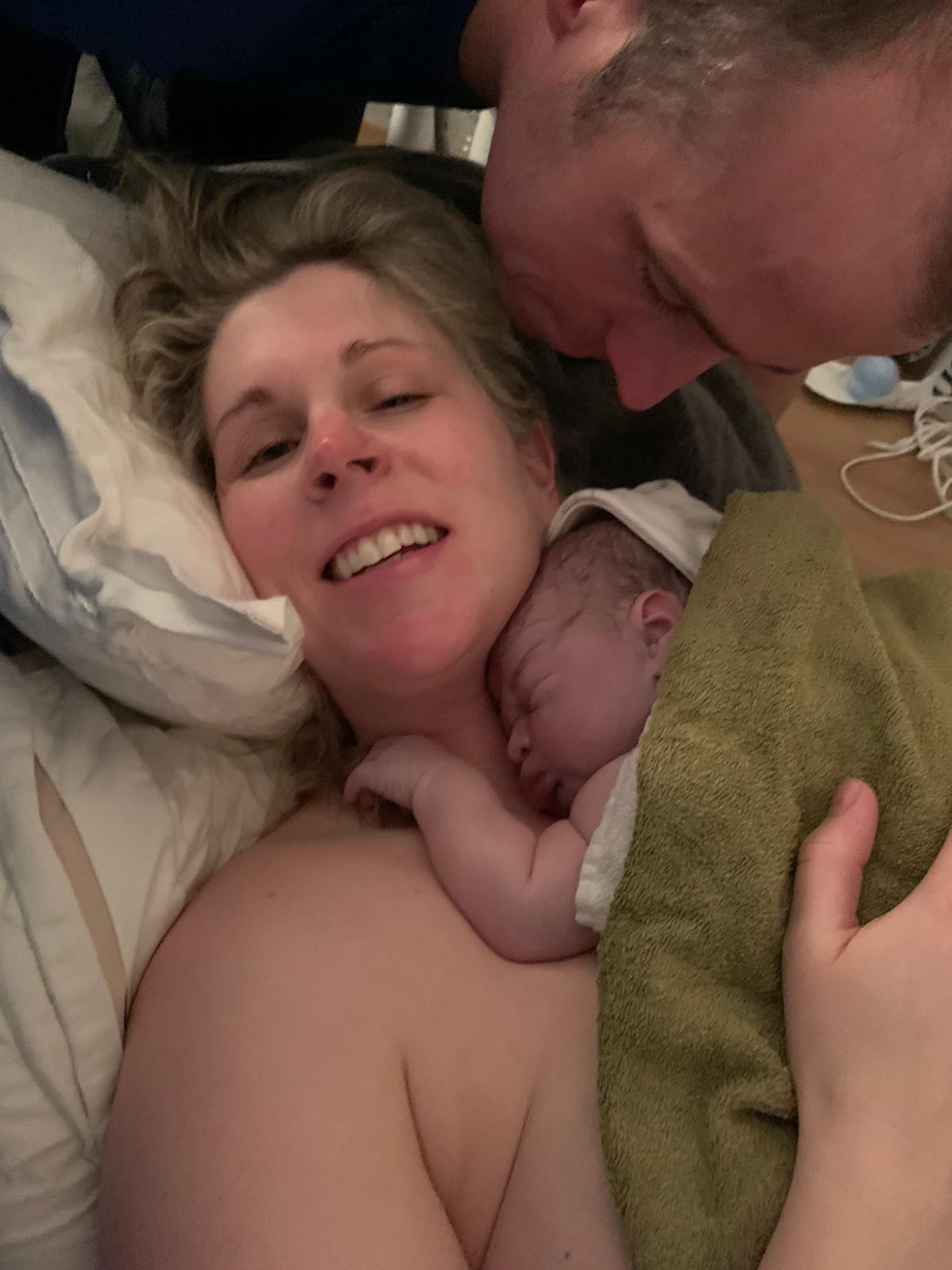 A man and woman are holding a newborn baby in their arms.