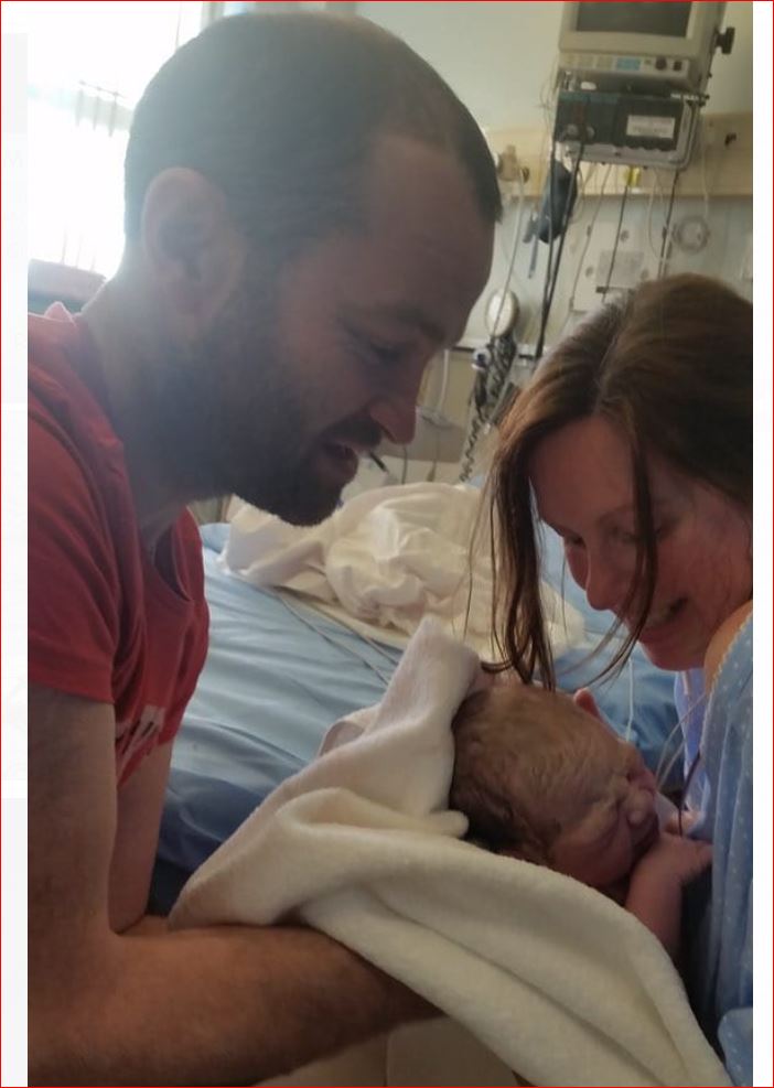 A man and woman are holding a baby in a hospital bed
