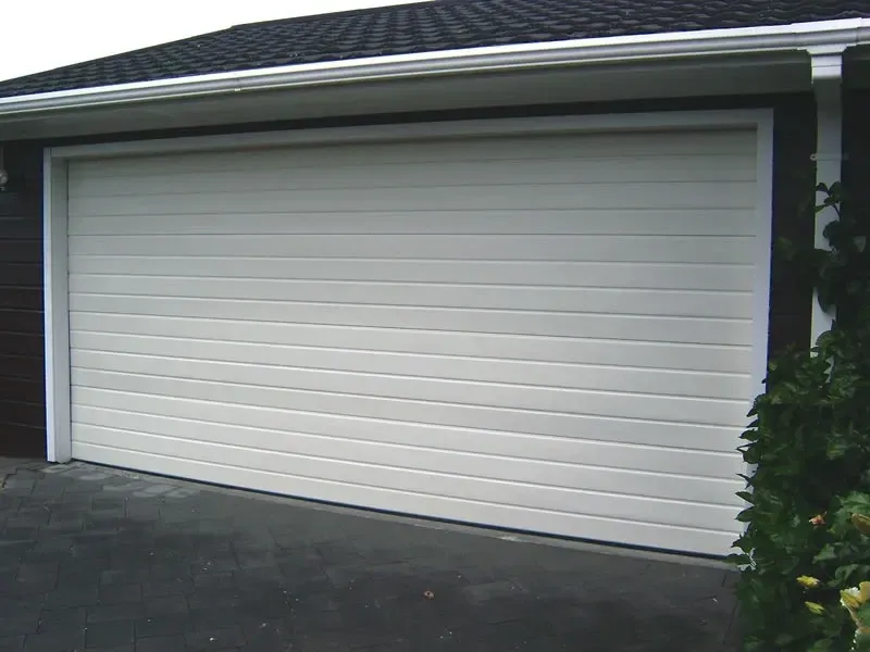 A white garage door is open in front of a house