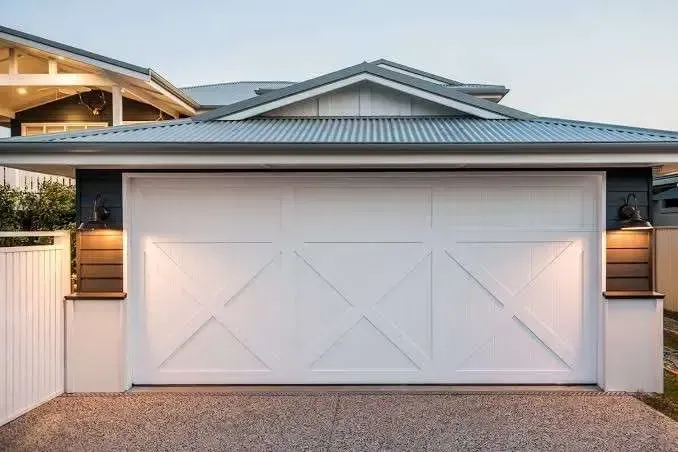 A white garage door is sitting in front of a house.