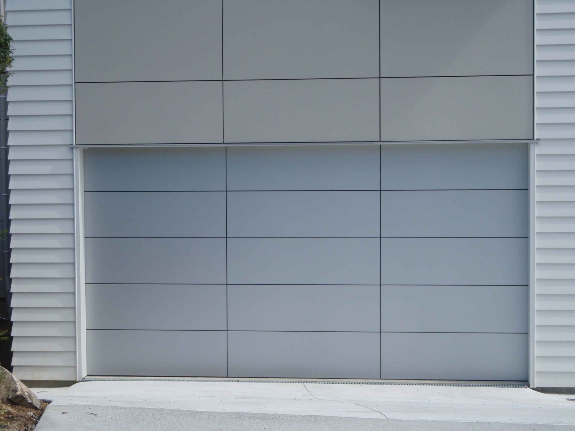 A white garage door with a concrete driveway in front of it