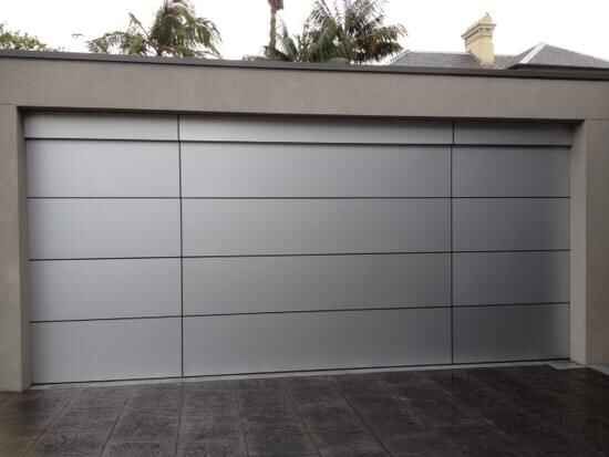 A gray garage door with a tiled driveway in front of it