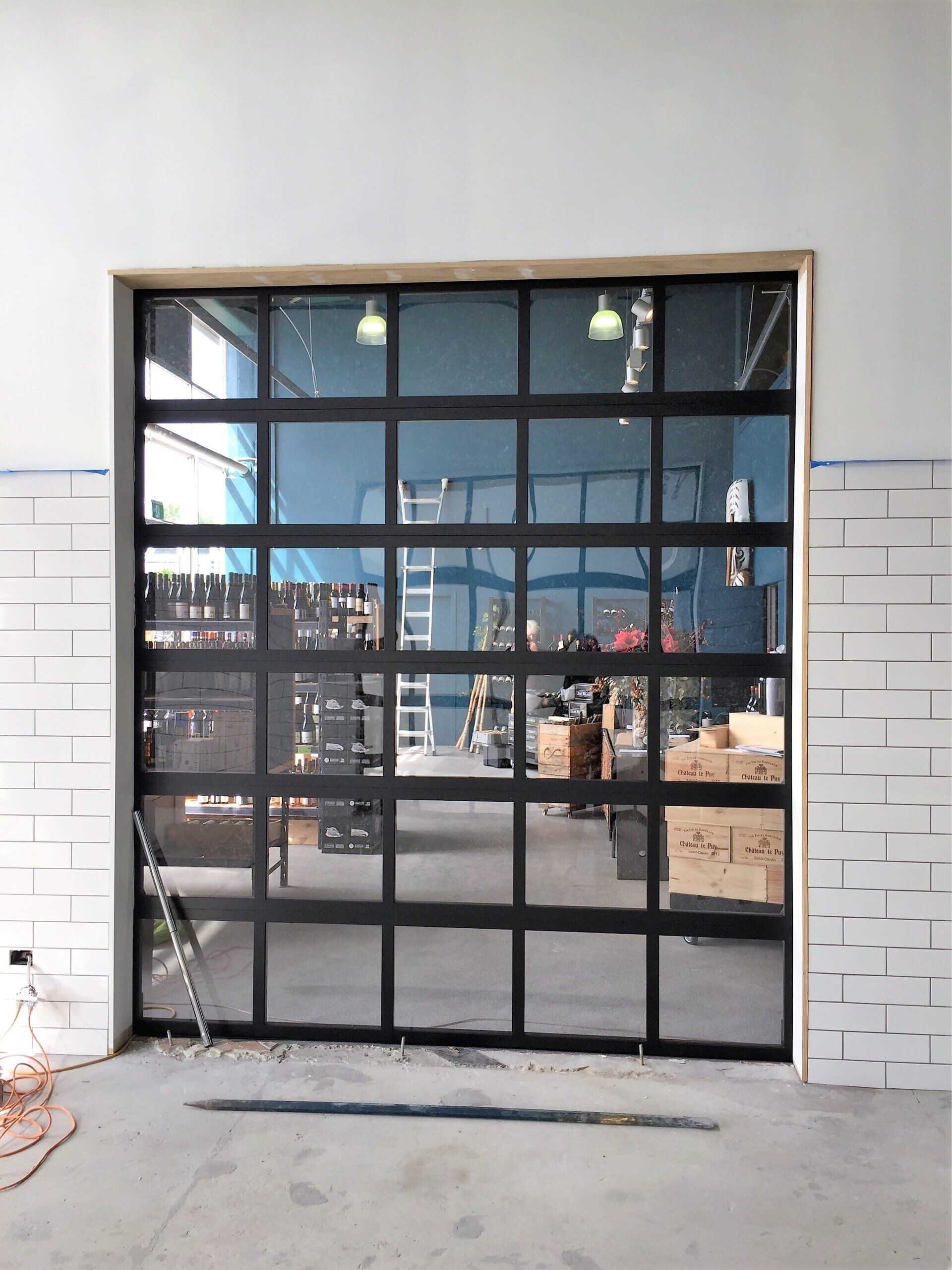 A large glass garage door is being installed in a building