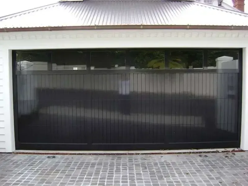 A white house with a black garage door and a brick driveway