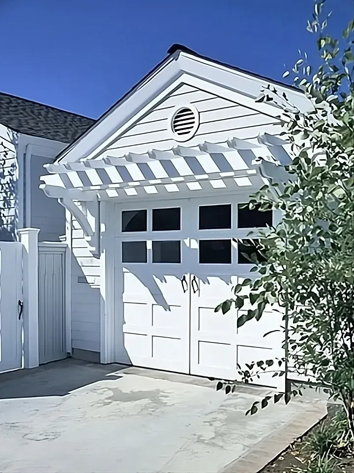 A white garage with a pergola over it