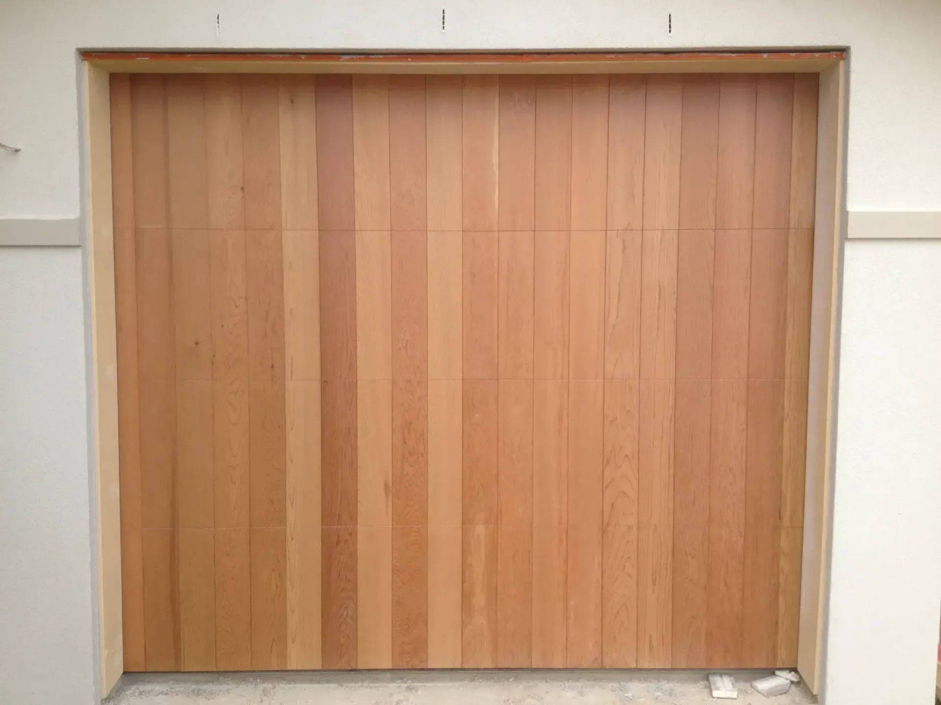 A wooden garage door is being installed on a house.