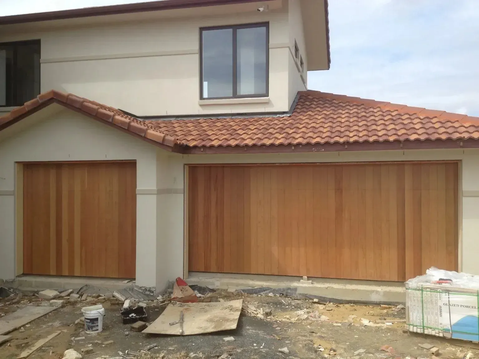 A house with a tiled roof and wooden sectional garage doors