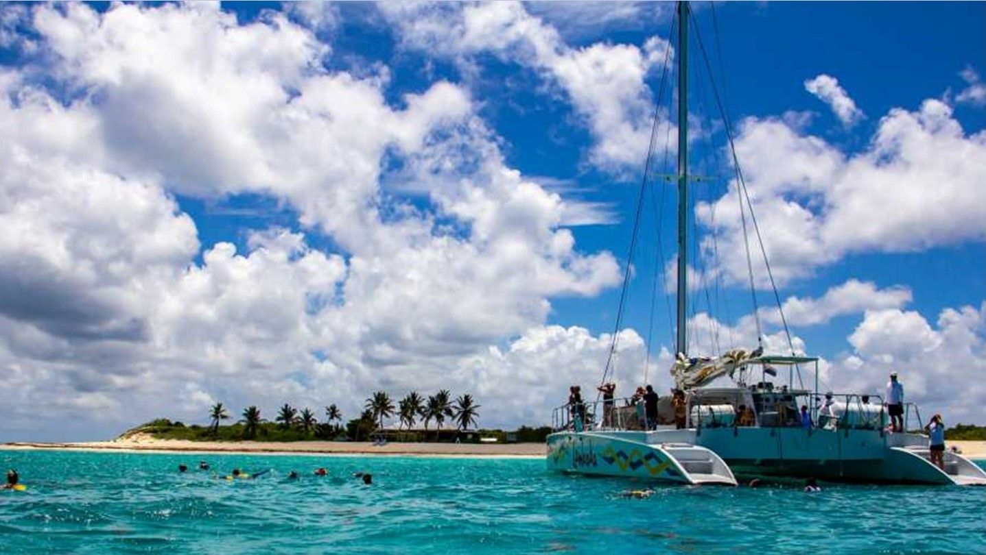 A sailboat is floating in the ocean near a small island.