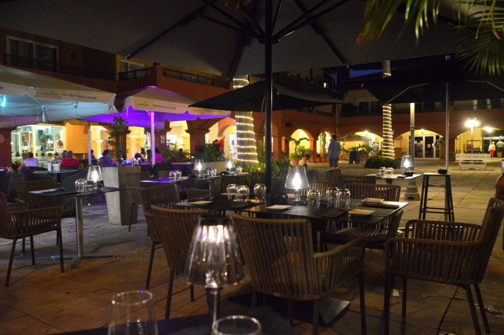 A restaurant with tables and chairs and umbrellas at night