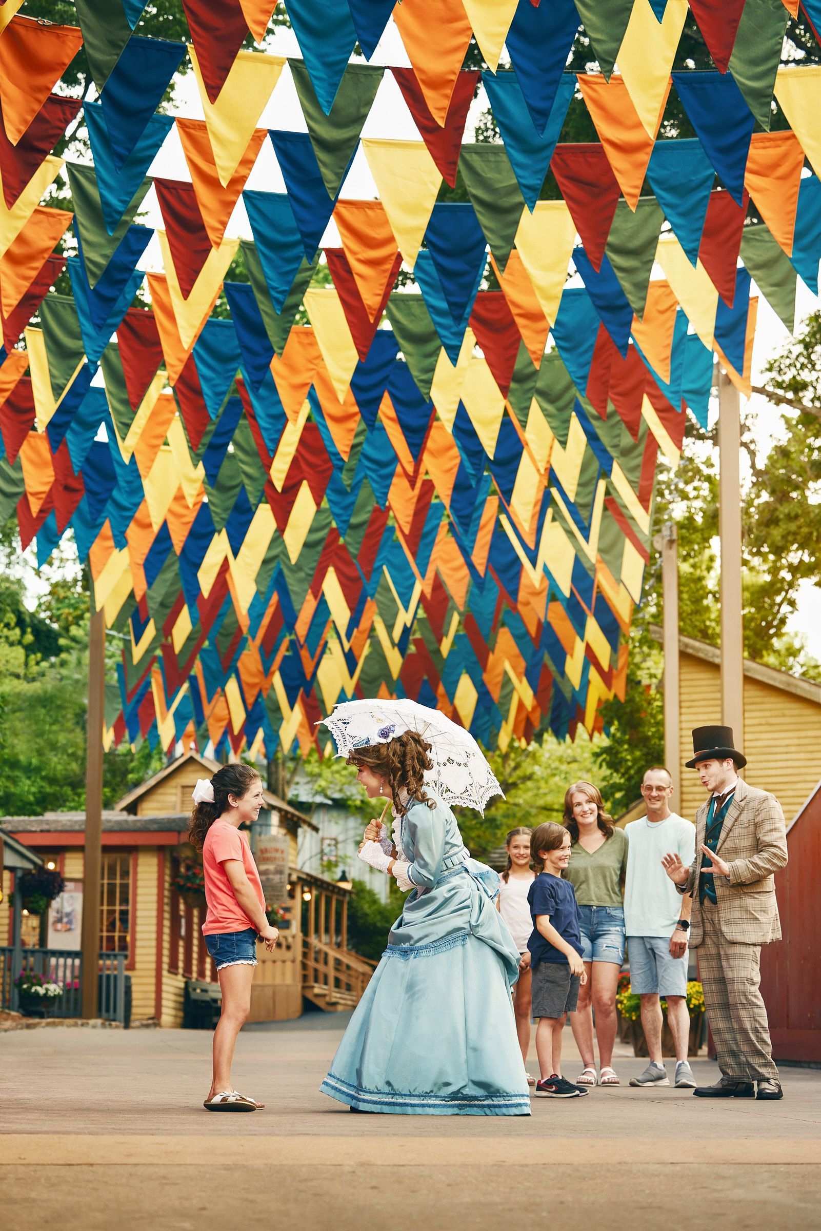 A woman in a blue dress is holding an umbrella in front of a group of people.