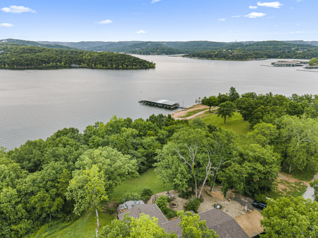 An aerial view of a lake surrounded by trees and a house.
