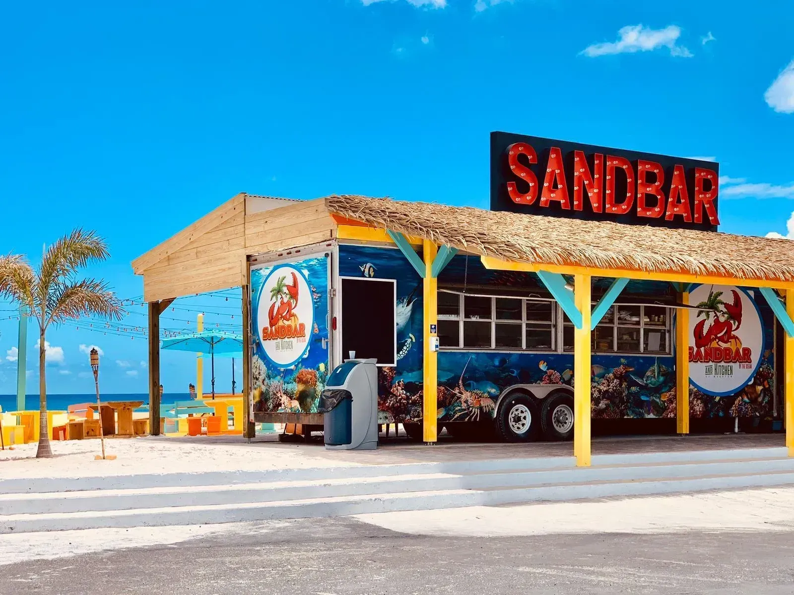A sandbar on the beach with a thatched roof