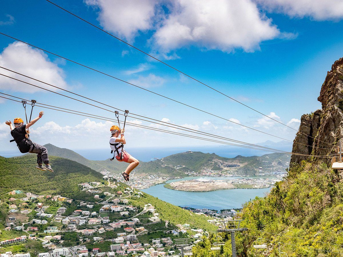A man and a woman are flying through the air on a zip line.