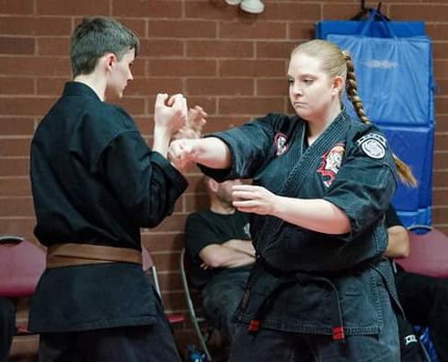 A man and a woman are practicing martial arts in a gym.